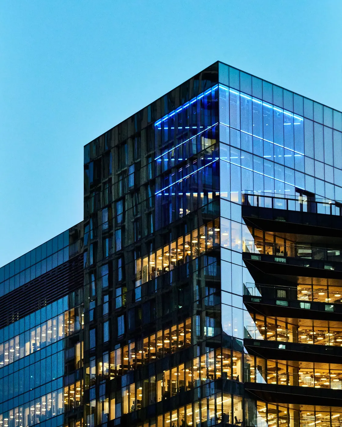 Modern glass office building lit up at dusk