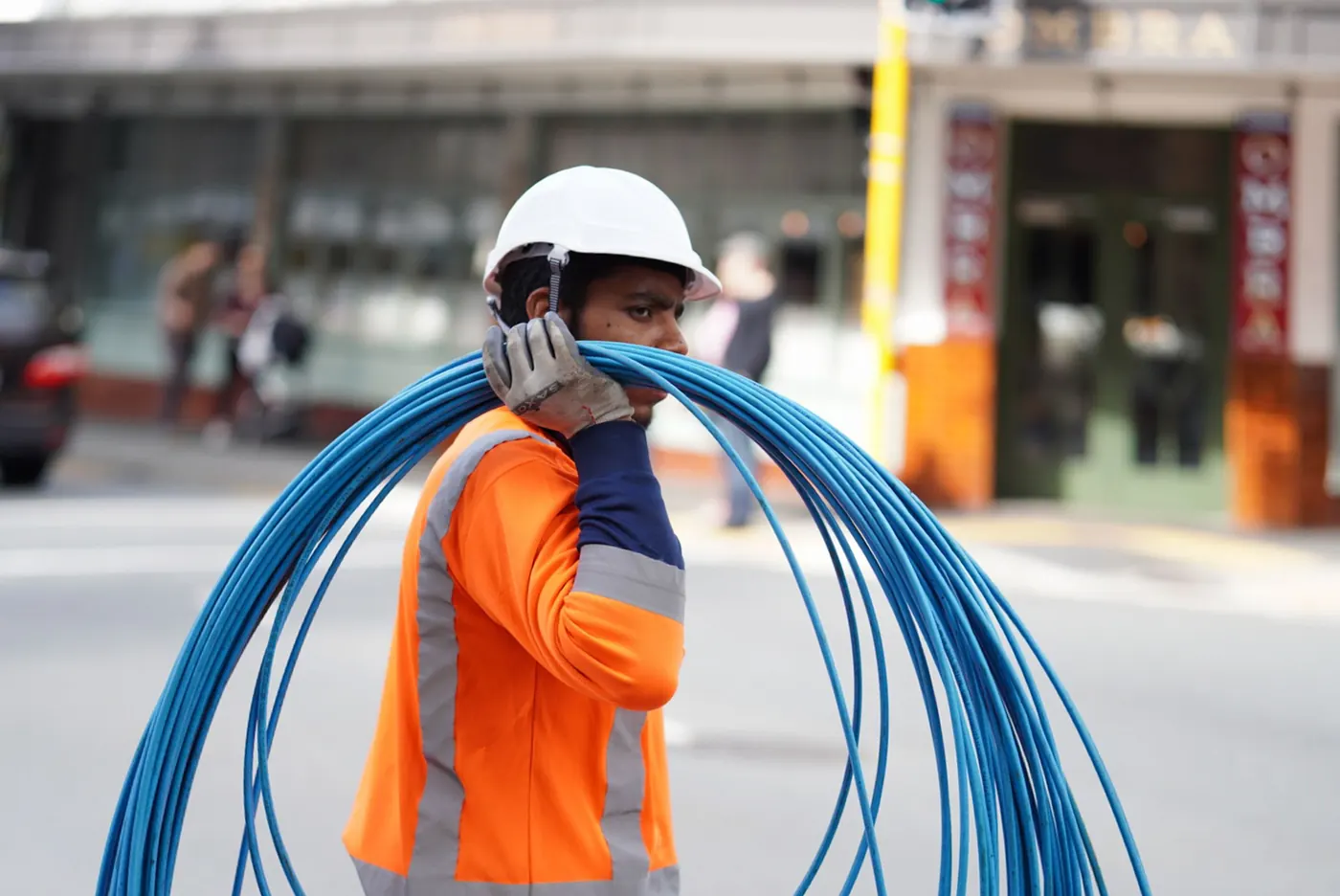 Field technician carrying a coil of fiber-optic cable