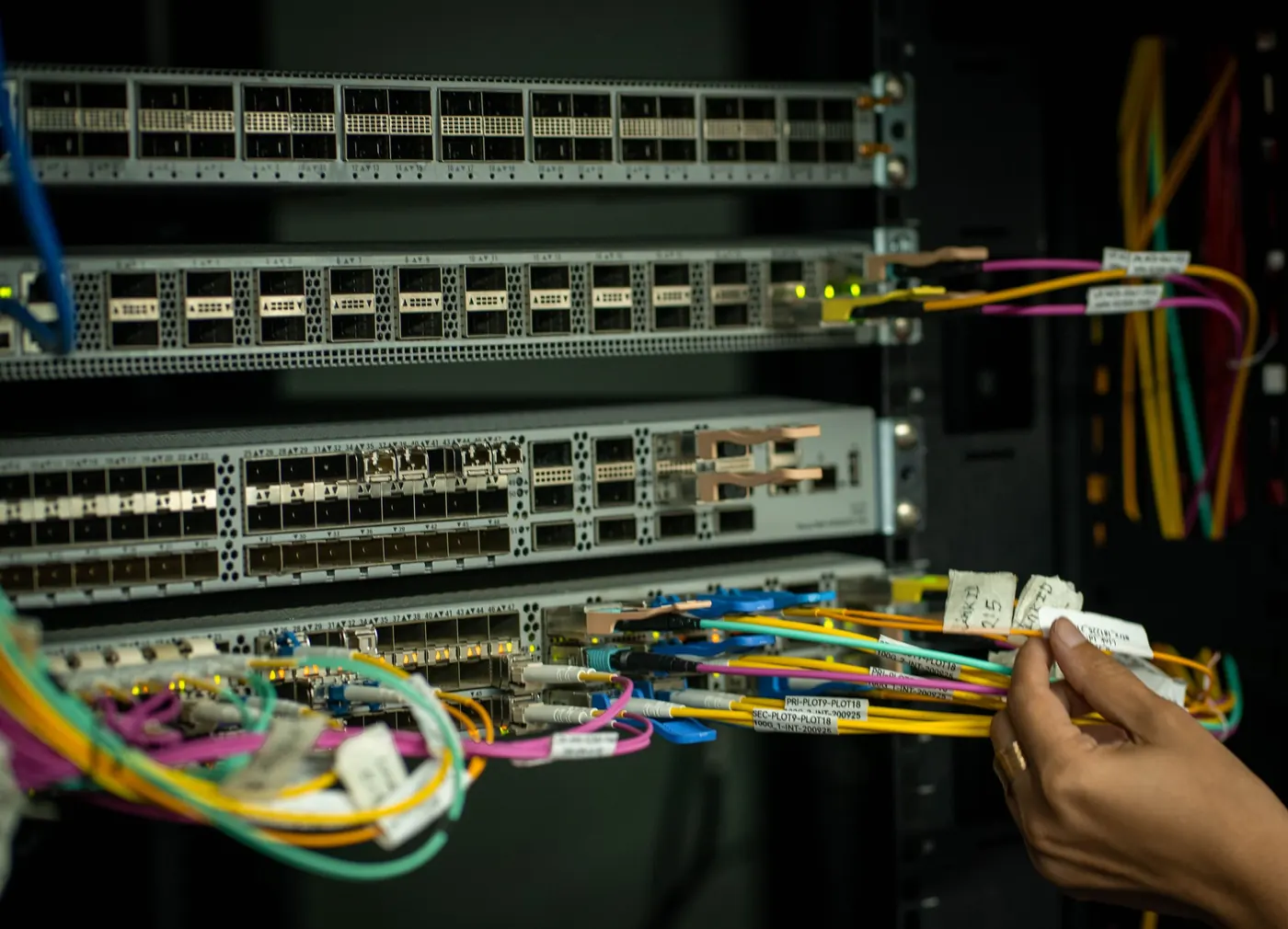 Technician connecting fiber-optic patch cables in a rack